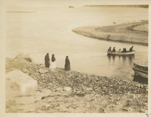 Image: People in small boat. Three women watching from shore